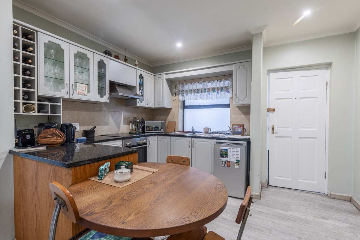 A functional kitchen featuring granite countertops, ample built-in cabinetry with an integrated wine rack, tiled backsplash, and recessed lighting.