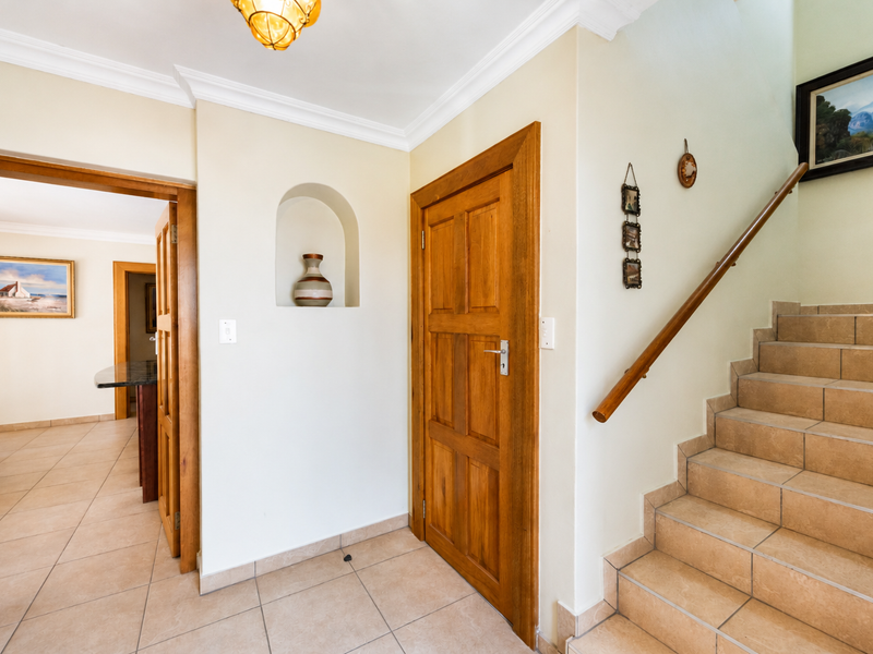 Welcoming entrance hall featuring tiled flooring, a wooden staircase with a handrail, and a decorative recessed wall niche.