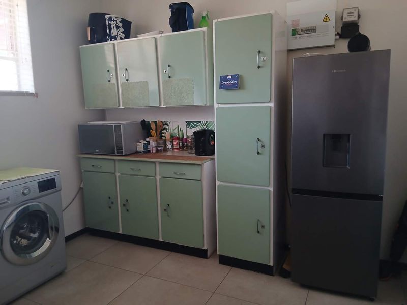 A functional laundry area featuring built-in mint green cabinetry, laminate countertops, and tiled flooring, providing practical storage and utility space.