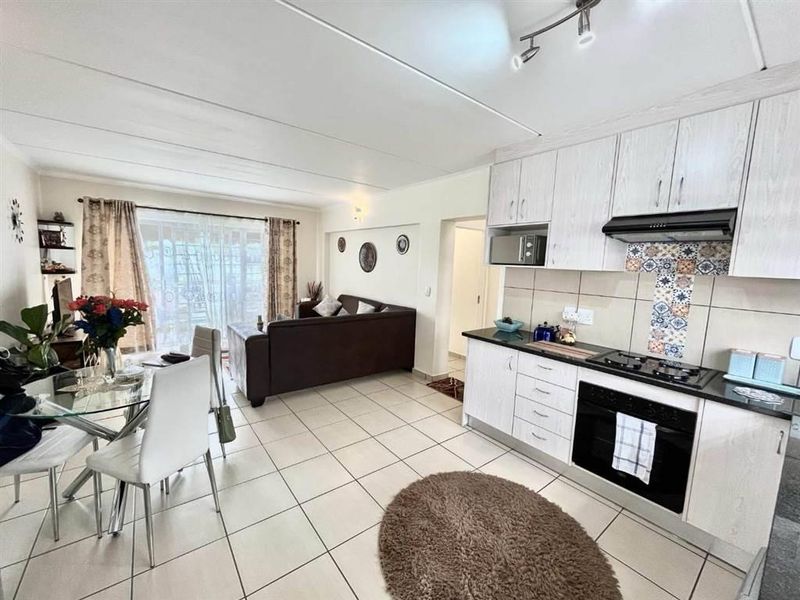 Open-plan living area featuring a modern kitchen with built-in cabinetry, gas hob, and oven, flowing into a bright dining and lounge space with sliding doors.