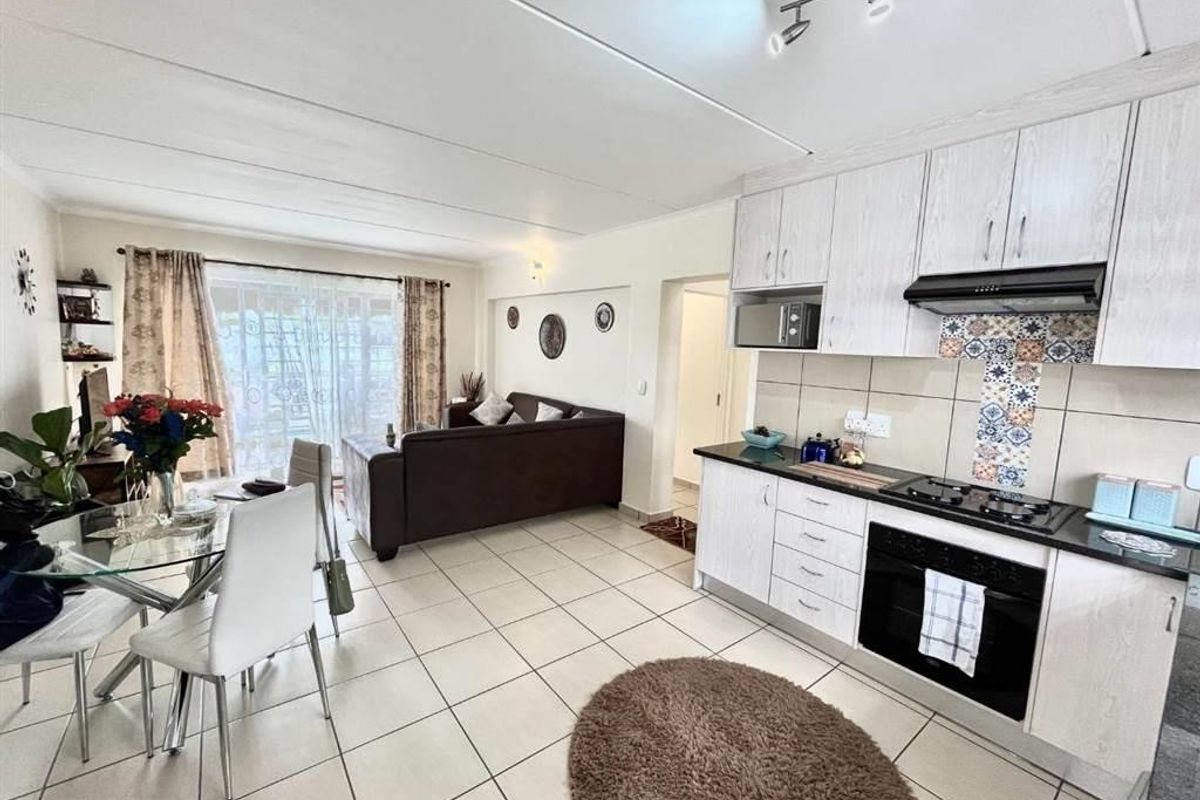 Open-plan living area featuring a modern kitchen with built-in cabinetry, gas hob, and oven, flowing into a bright dining and lounge space with sliding doors.