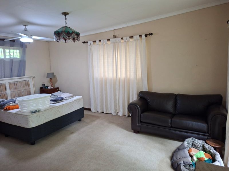 Spacious bedroom featuring neutral wall tones, carpeted flooring, and a ceiling fan, offering a blank canvas for personalization and interior updates.
