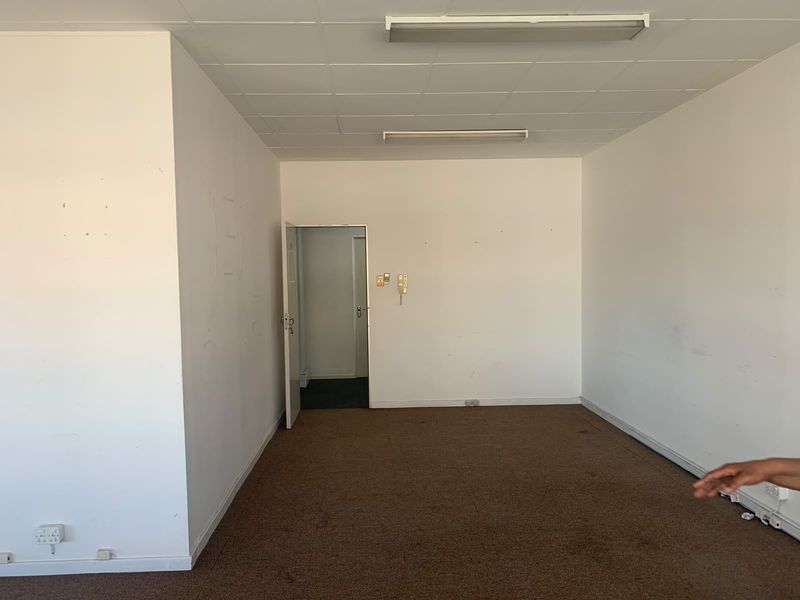 An empty office space featuring a suspended ceiling, fluorescent lighting, and carpet flooring, ready for customization or professional fit-out.