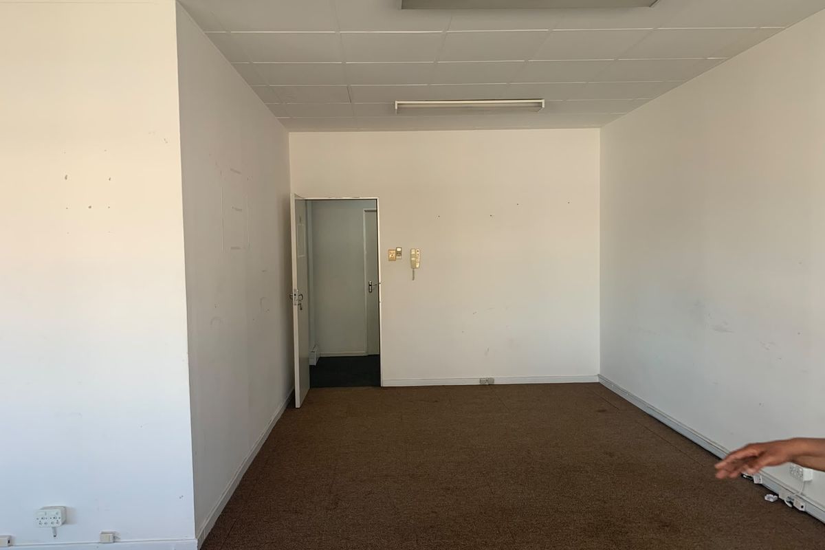 An empty office space featuring a suspended ceiling, fluorescent lighting, and carpet flooring, ready for customization or professional fit-out.