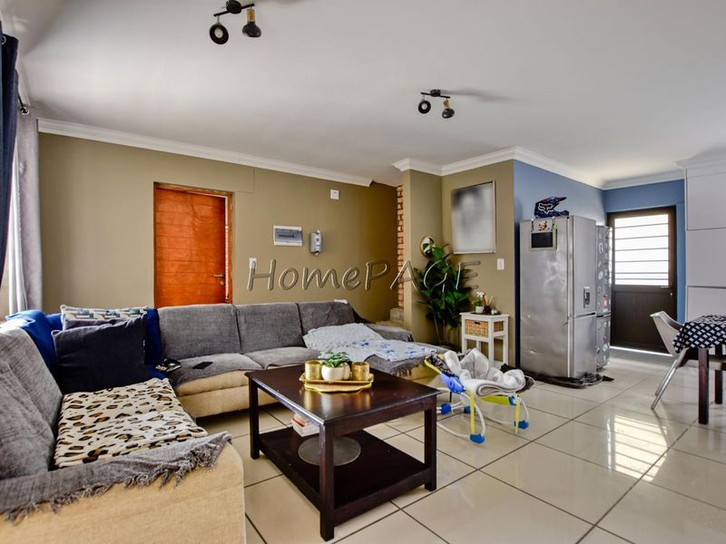 Open-plan living area featuring tiled flooring, cove cornicing, and track lighting, providing a functional and connected space for relaxation and dining.