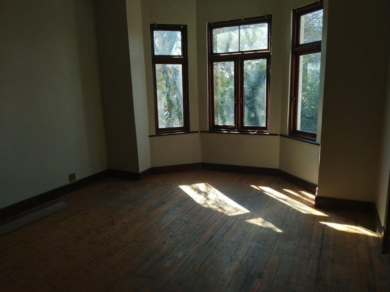 An empty bedroom featuring original timber flooring and a classic bay window with timber frames, offering a bright and character-filled space.