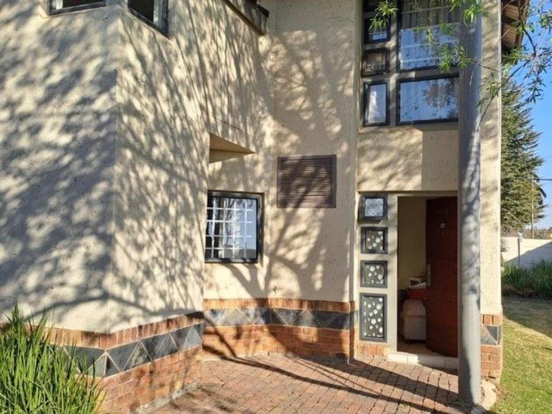 Exterior view of the apartment entrance featuring brick paving, decorative brick accents, and multi-pane windows with a tiled roof structure.