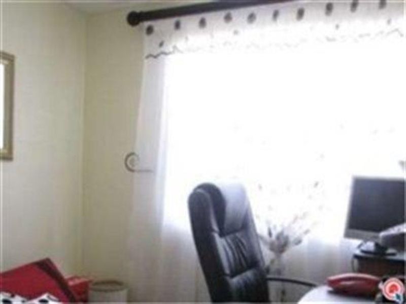 A small office space featuring a window with a curtain rod, providing natural light to the room.