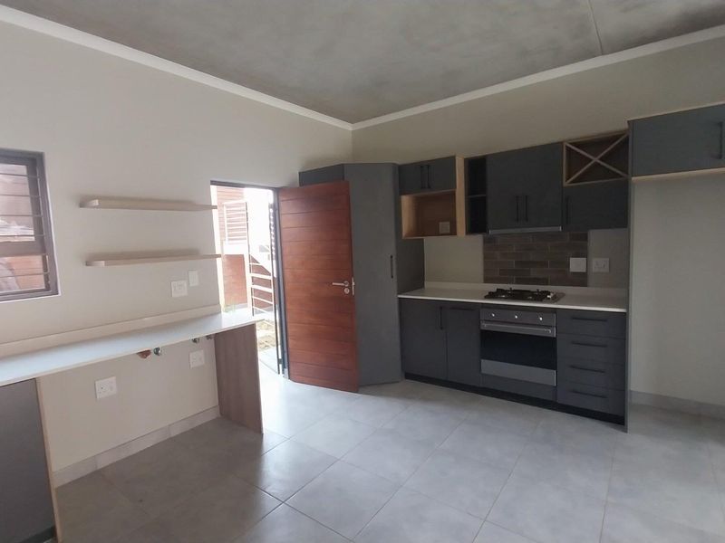 Modern kitchen featuring dark grey cabinetry, built-in gas hob and oven, tiled flooring, and a functional workspace with a stainless steel sink.