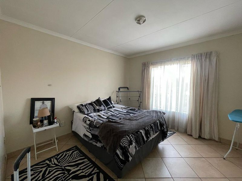 A functional bedroom featuring tiled flooring and neutral wall tones, offering a blank canvas for personalization and interior design updates.