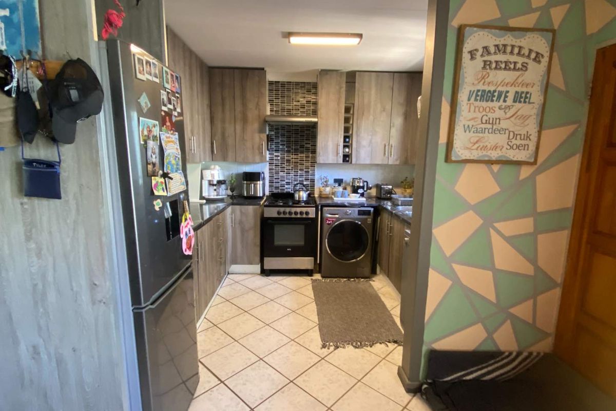 A functional kitchen featuring wood-look cabinetry, a mosaic tile backsplash, a built-in oven with extractor fan, and tiled flooring.