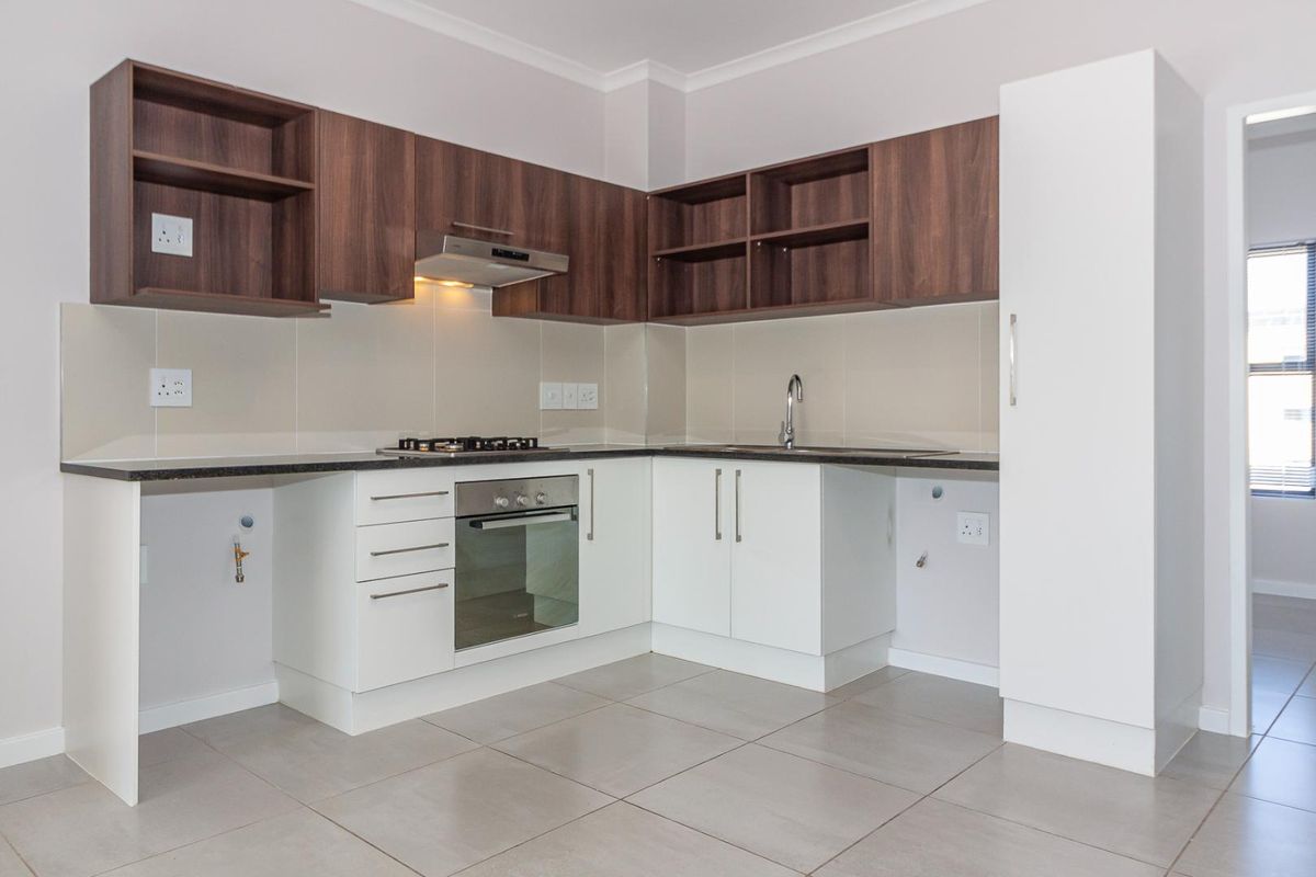 Modern kitchen featuring dark wood upper cabinets, white lower cabinetry, gas hob, electric oven, and tiled flooring with dedicated appliance plumbing connections.