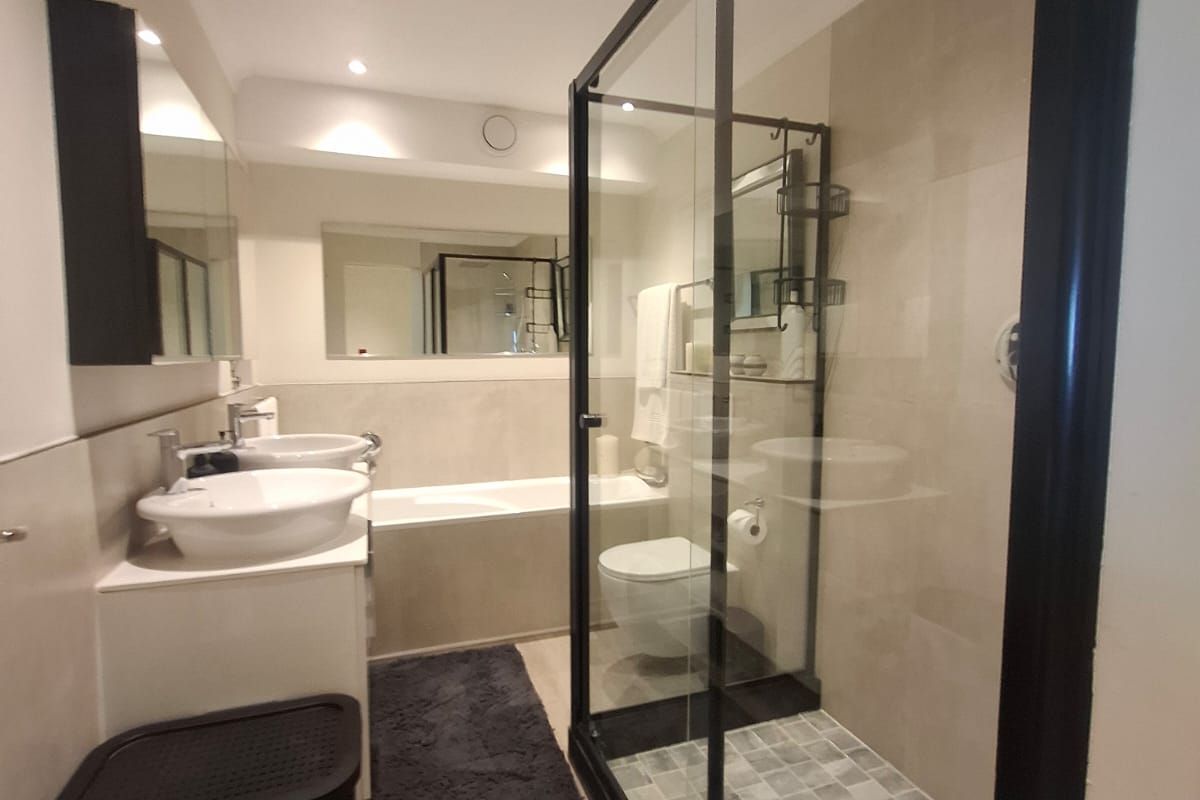 Modern bathroom featuring a double vanity, built-in bathtub, and a spacious walk-in shower with a sleek black frame.