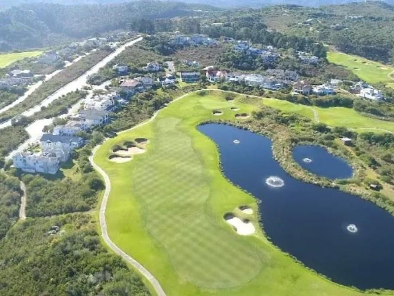 Aerial view of a residential estate featuring a golf course, water hazards, and surrounding natural landscape.