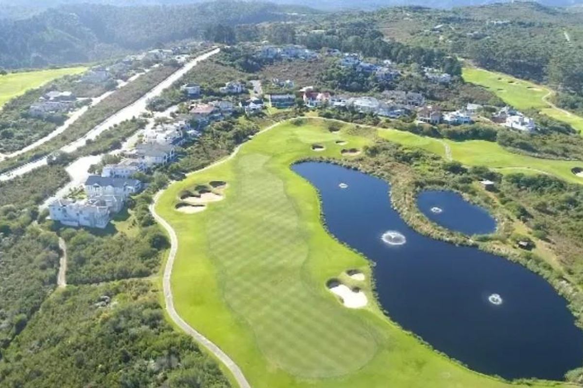 Aerial view of a residential estate featuring a golf course, water hazards, and surrounding natural landscape.