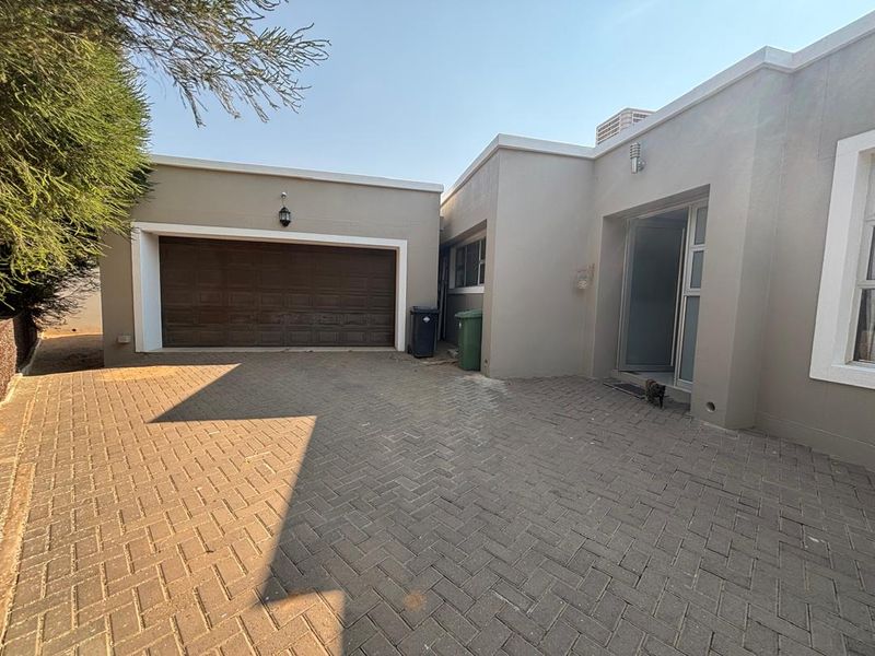 Front exterior view of the property featuring a paved driveway, double garage, and main entrance access.
