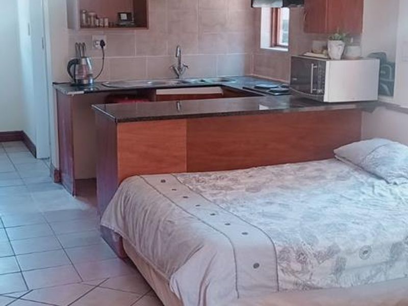 Open-plan studio apartment featuring a compact kitchen with built-in cabinetry, granite countertops, and tiled flooring throughout.