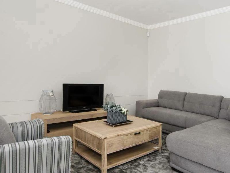 A well-maintained living room featuring crown molding and a neutral wall finish, providing a clean and comfortable space.