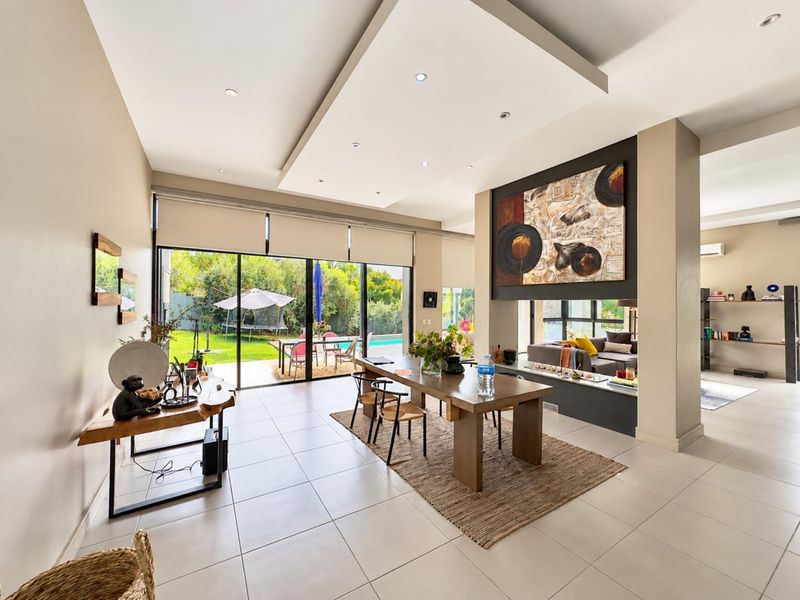 Spacious open-plan living and dining area featuring tiled floors, a modern recessed ceiling with downlights, and large sliding doors opening to the garden.