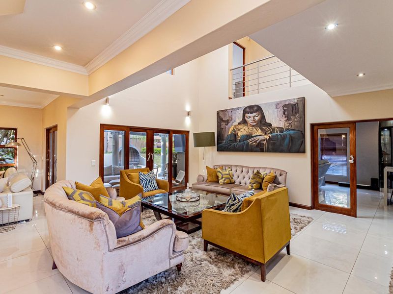 Spacious double-volume living room featuring polished porcelain floor tiles, recessed lighting, and large timber-framed glass doors leading to the outdoor area.