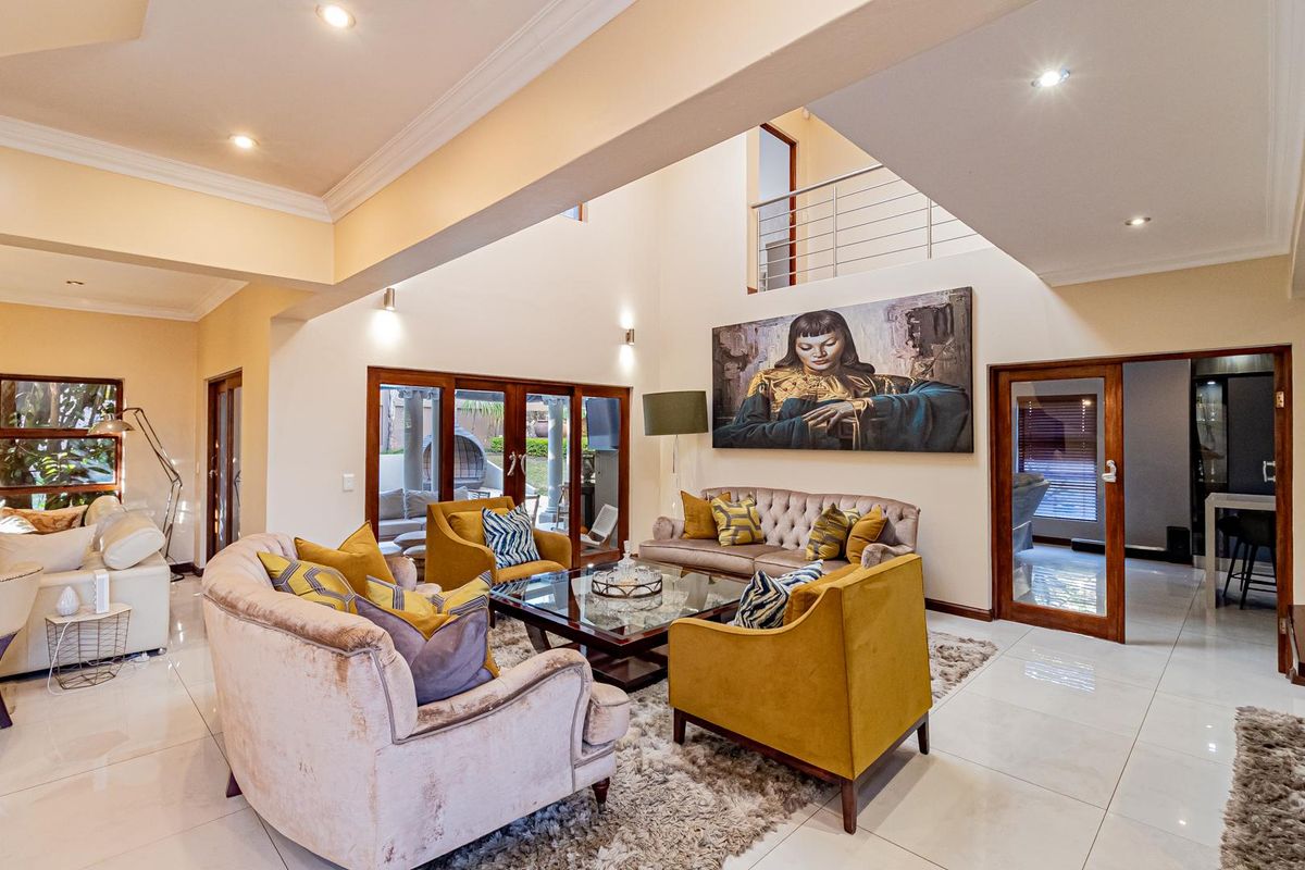 Spacious double-volume living room featuring polished porcelain floor tiles, recessed lighting, and large timber-framed glass doors leading to the outdoor area.