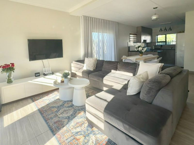 Spacious open-plan living area featuring tiled floors, modern kitchen cabinetry, and seamless flow to the outdoor patio through sliding glass doors.