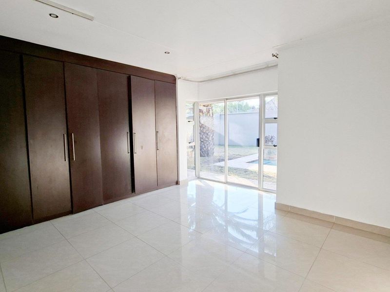 Spacious bedroom featuring large built-in cupboards, polished tile flooring, and a sliding glass door providing direct access to the outdoor area.