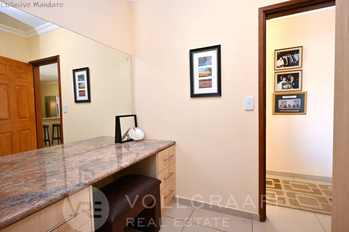 A functional dressing area featuring a built-in vanity with a granite countertop, integrated drawers, and a large wall-mounted mirror.
