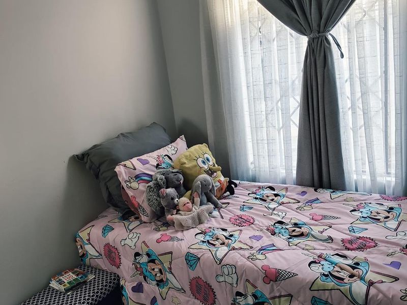 A cozy bedroom featuring a window with security bars and neutral wall finishes, providing a comfortable and functional living space.