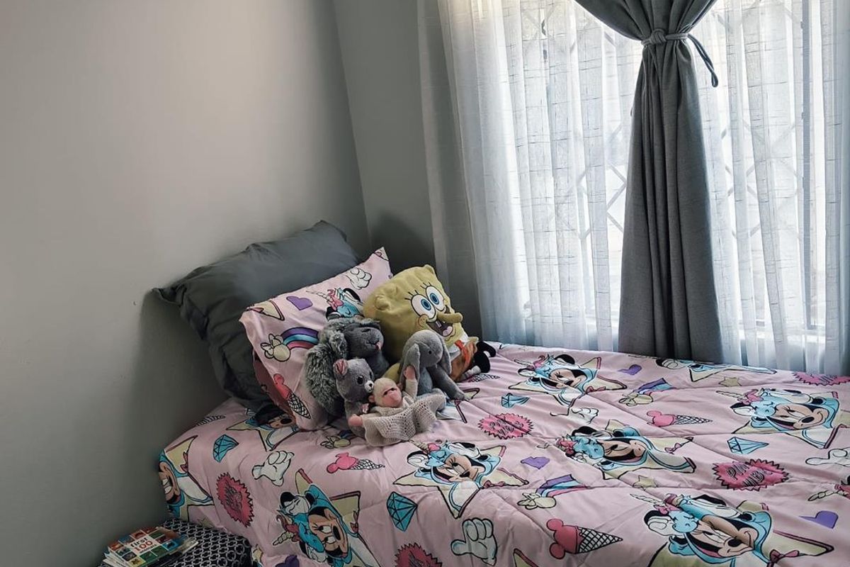 A cozy bedroom featuring a window with security bars and neutral wall finishes, providing a comfortable and functional living space.