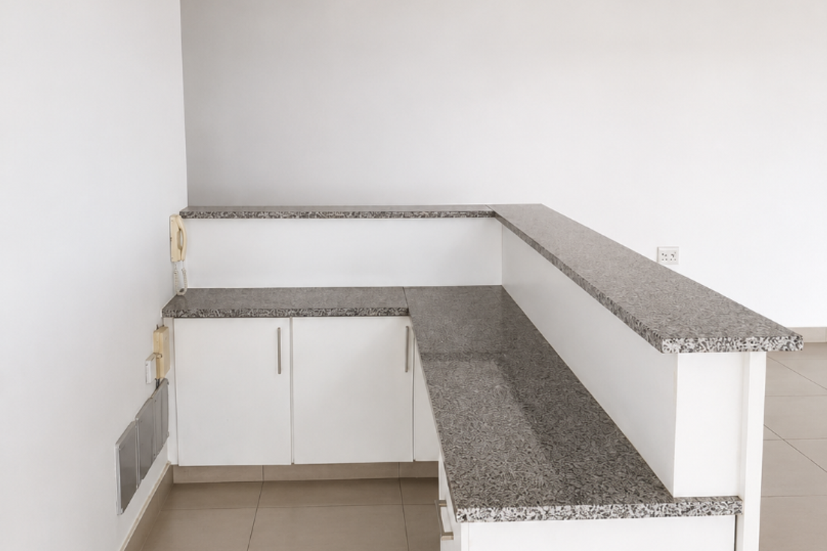 A clean, modern office reception or workstation area featuring built-in cabinetry with granite countertops, tiled flooring, and a suspended ceiling with recessed lighting.