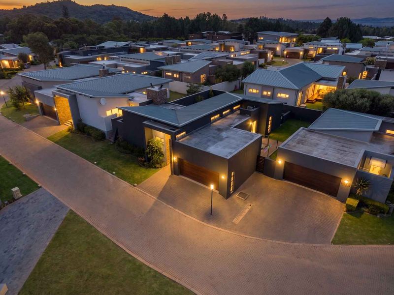 An elevated aerial view of a modern residential estate at dusk, showcasing contemporary homes with paved driveways, garages, and well-maintained landscaping.