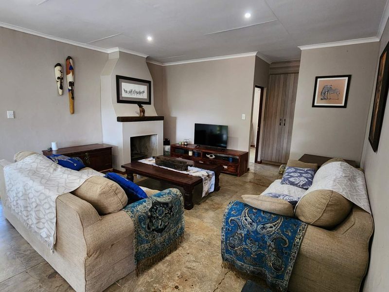 A comfortable living room featuring a built-in fireplace, recessed downlights, and tiled flooring, with direct access to an outdoor patio area.