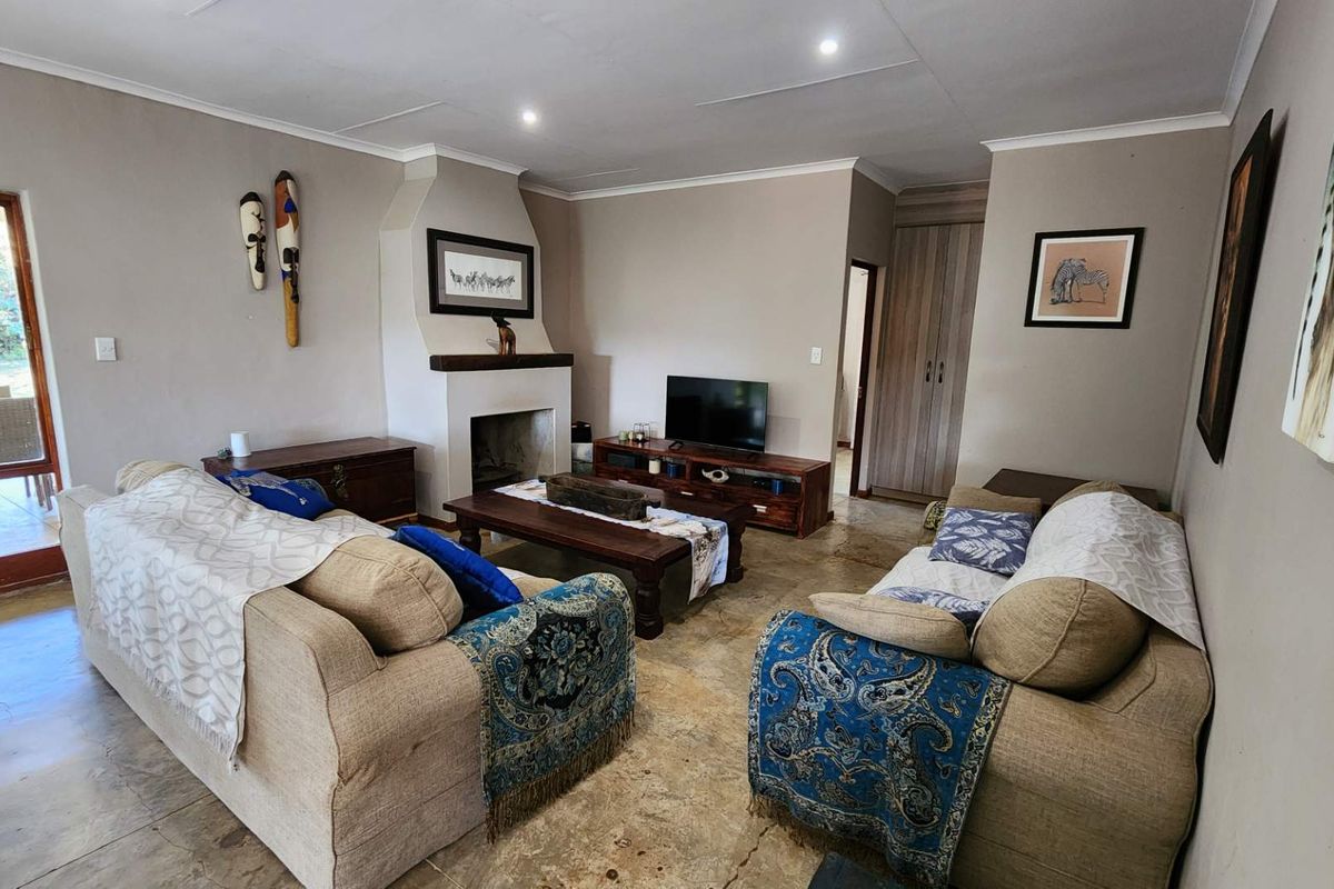 A comfortable living room featuring a built-in fireplace, recessed downlights, and tiled flooring, with direct access to an outdoor patio area.
