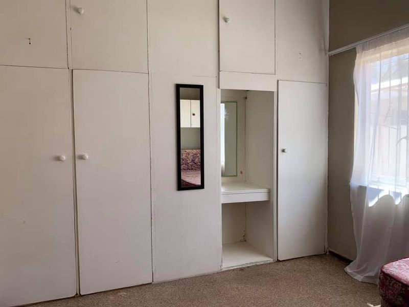 Bedroom featuring extensive floor-to-ceiling built-in cupboards with an integrated vanity area and carpeted flooring.
