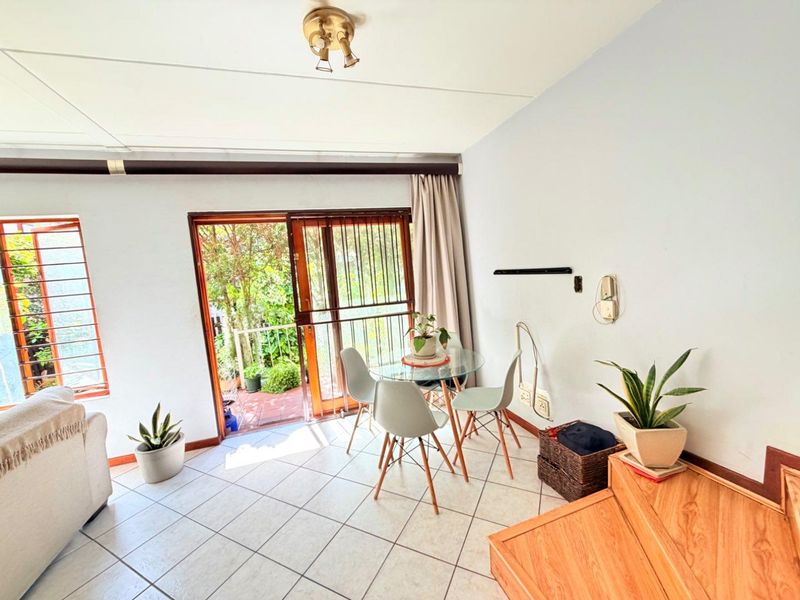 A bright living area featuring tiled flooring and a sliding glass door providing direct access to an outdoor patio space.