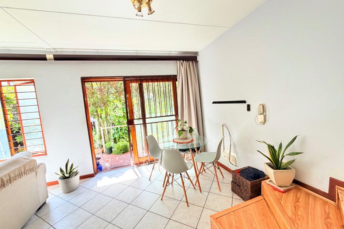 A bright living area featuring tiled flooring and a sliding glass door providing direct access to an outdoor patio space.