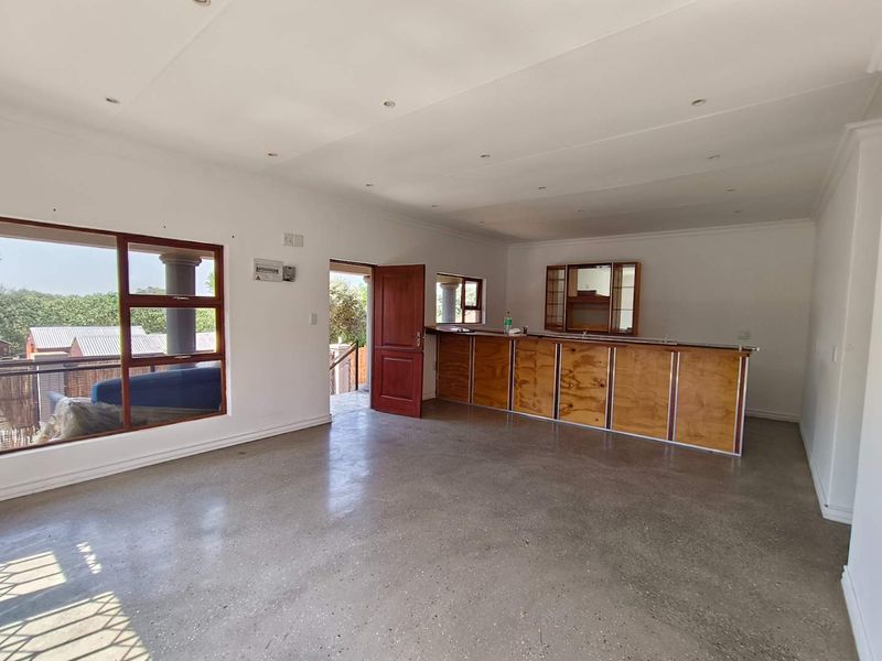 Spacious living area featuring a built-in bar, polished concrete flooring, and large windows providing natural light and outdoor access.