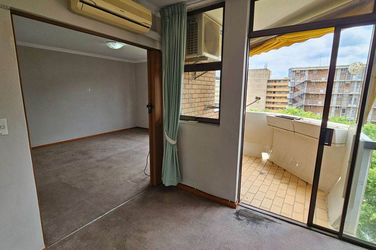 Living area featuring carpeted flooring, wall-mounted air conditioning, and direct access to a private balcony with tiled flooring.