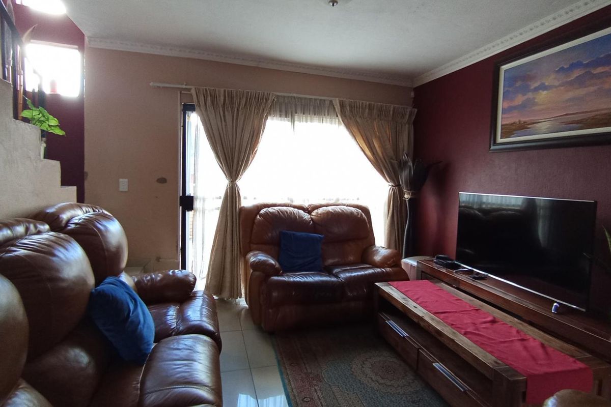 A comfortable living room featuring tiled flooring, decorative ceiling cornices, and a sliding glass door providing access to the outdoor area.