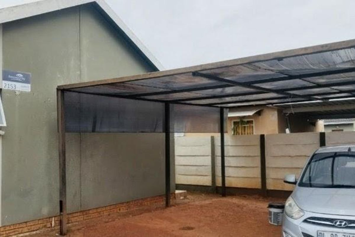 Front exterior view of the property featuring a metal carport structure and a precast concrete boundary wall.