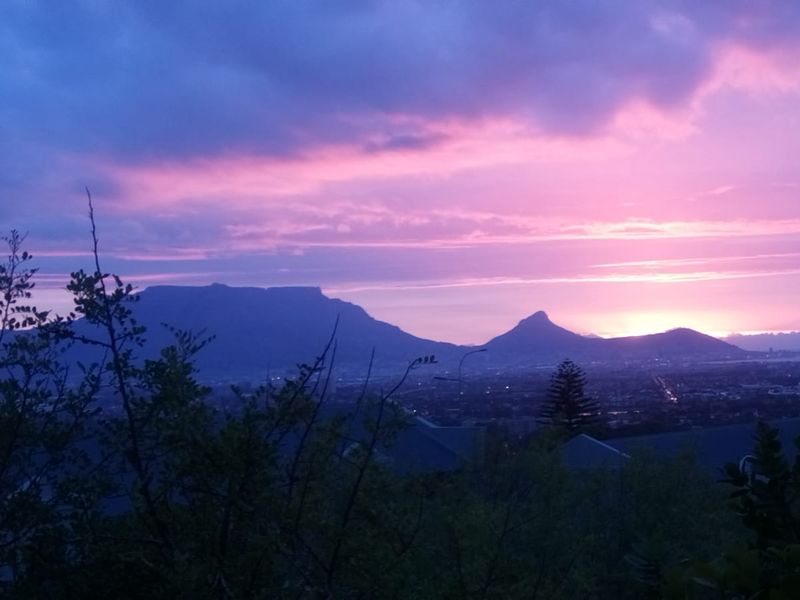 A scenic sunset view overlooking the city and mountain range, showcasing the property's elevated position and natural surroundings.