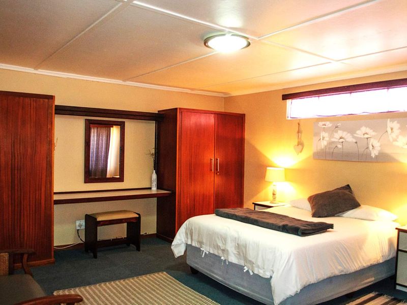 A bedroom featuring built-in wooden cupboards and a matching vanity unit with a tiled ceiling.