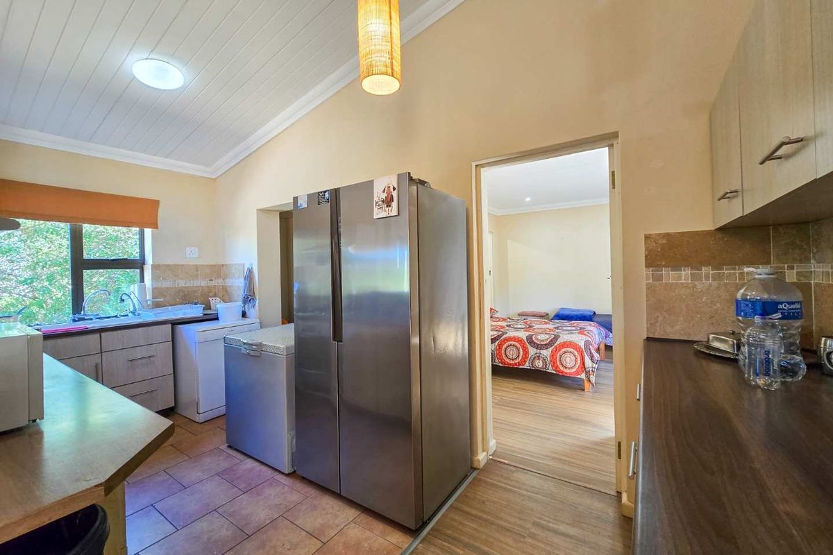 Functional kitchen featuring built-in cabinetry, laminate countertops, tiled backsplash, and a double sink, with direct access to an adjacent bedroom.