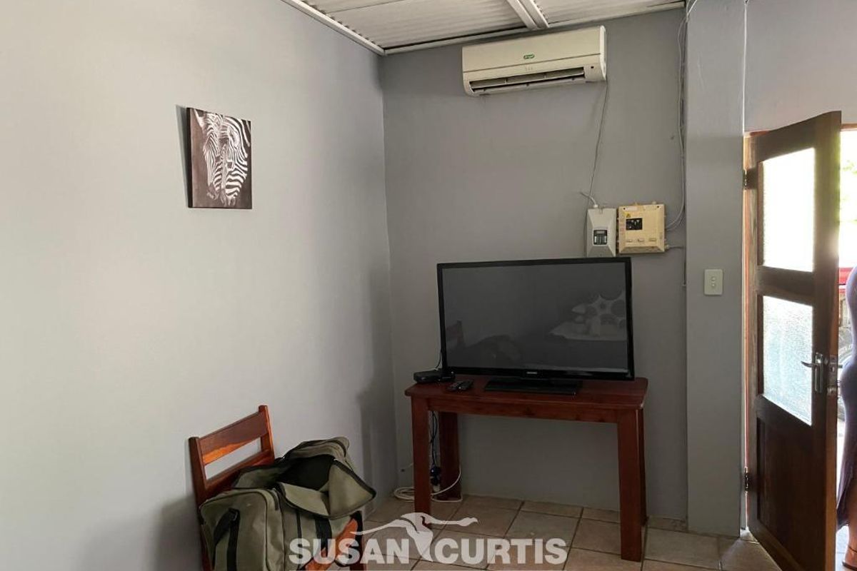 A functional living area featuring tiled flooring, a wall-mounted air conditioning unit, and direct access to an outdoor space.