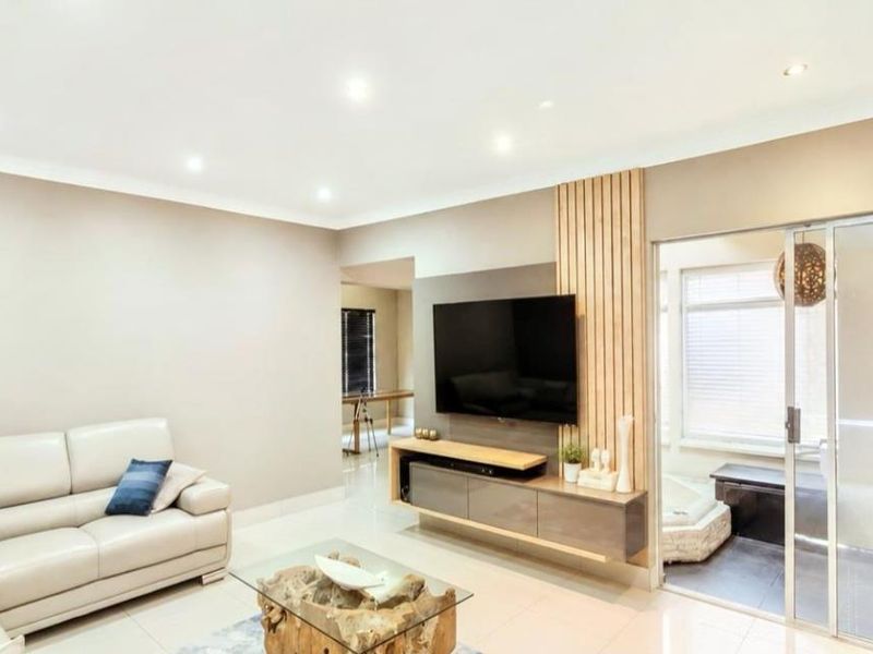 Modern living room featuring tiled floors, recessed lighting, and a stylish timber slat feature wall with a built-in media console.