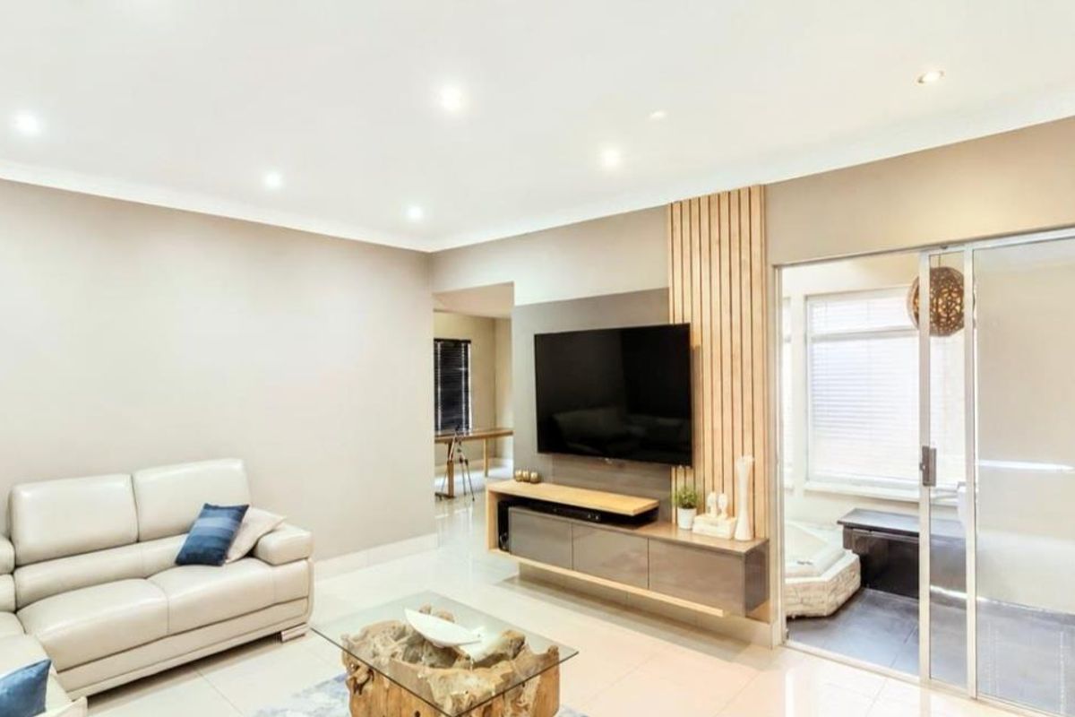 Modern living room featuring tiled floors, recessed lighting, and a stylish timber slat feature wall with a built-in media console.