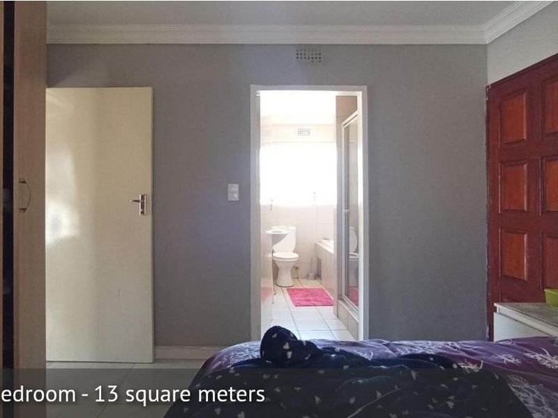 Main bedroom featuring a built-in wardrobe and direct access to an en-suite bathroom with neutral wall finishes.