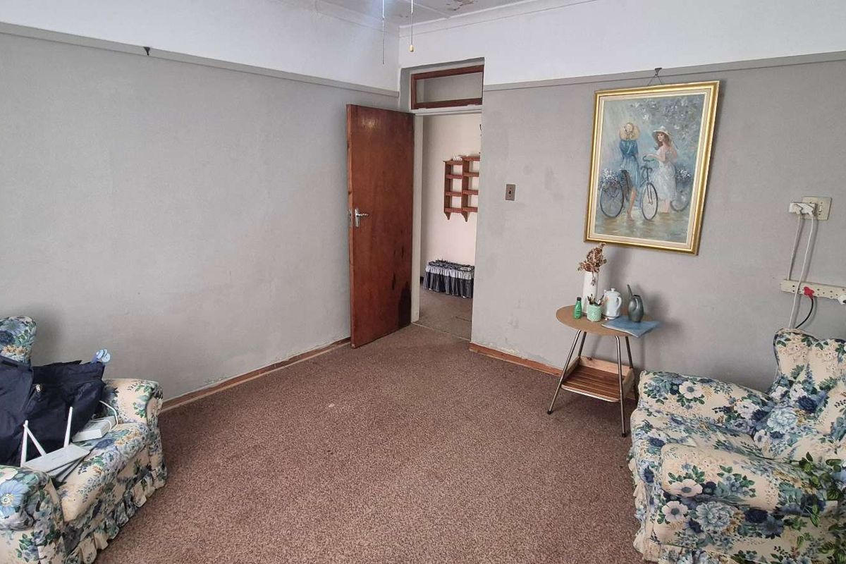A living room space featuring carpeted flooring, neutral wall finishes, and a doorway leading to an adjacent room.