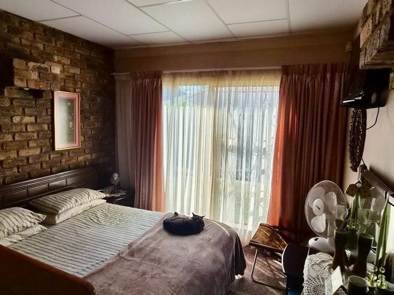A bedroom featuring an exposed brick feature wall and a sliding glass door providing natural light and access to the exterior.
